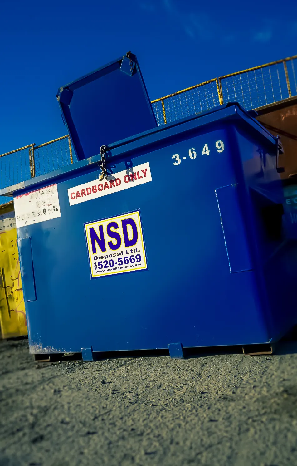 Blue NSD front-end bin labelled “Cardboard Only” with its lid open